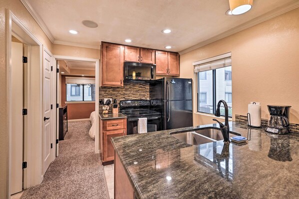 A modern kitchen with granite countertops, stainless steel appliances, and wooden cabinets.