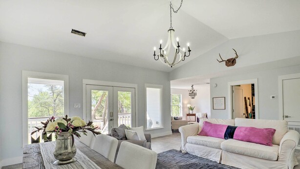 A spacious living room with a white sofa, a dining table with a vase of flowers, and a chandelier. - 'blackberry Roost' Home ~ 4 Mi to Downtown Salado (Salado)