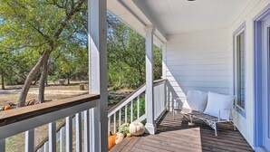 A porch with white railings, a wooden deck, and a white chair with cushions. - 'blackberry Roost' Home ~ 4 Mi to Downtown Salado (Salado)