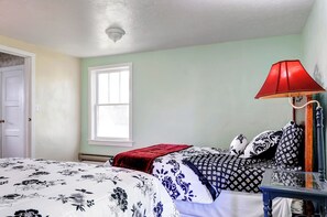 Un dormitorio con cama, ventana, lámpara roja y mesita de noche.