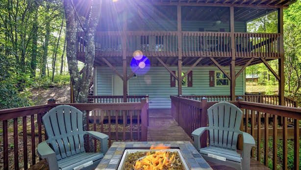 A deck with two Adirondack chairs and a fire pit.