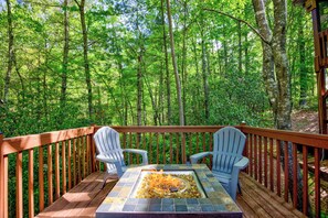 A deck with two Adirondack chairs and a fire pit.