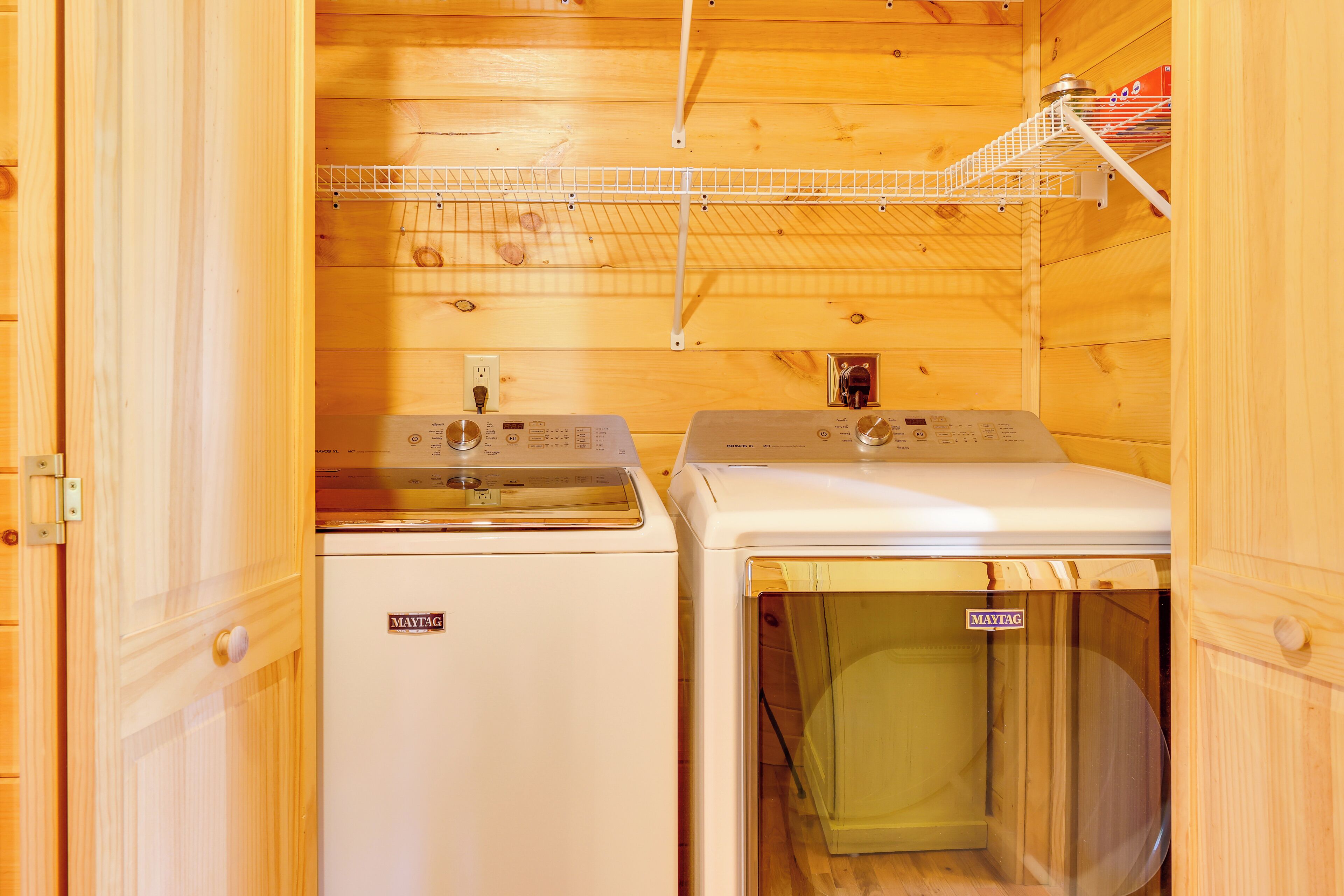 Une petite buanderie équipée de deux machines à laver, d’un étendoir et dotée de murs en bois.