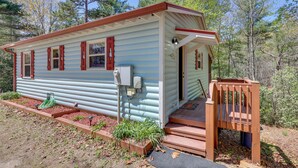 A small, single-story cabin with a front porch and a small deck.