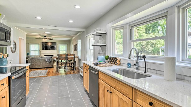 A modern kitchen with a dishwasher, sink, and a dining area with a table and chairs. - Chic Charlotte Retreat < 3 Miles to Downtown! (Charlotte)