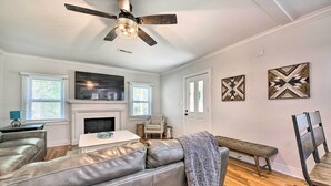 A living room with a leather sofa, a bench, a fireplace, and two wall-mounted artworks. - Chic Charlotte Retreat < 3 Miles to Downtown! (Charlotte)