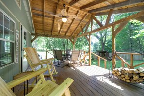 A wooden deck with outdoor furniture, a ceiling fan, and a stack of firewood.