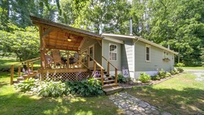 A cabin with a wooden deck, a stone pathway, and a garden with various plants. - Charming Waynesville Cottage < 2 Mi to Main St (Waynesville)