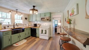 A kitchen with green cabinets, a white stove, a microwave, and a wooden countertop. - Charming Waynesville Cottage < 2 Mi to Main St (Waynesville)