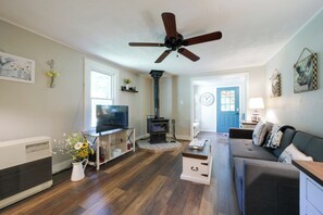 A living room with a TV, fireplace, sofa, and ceiling fan.
