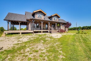 A large, two-story log cabin with a covered porch and a landscaped yard.