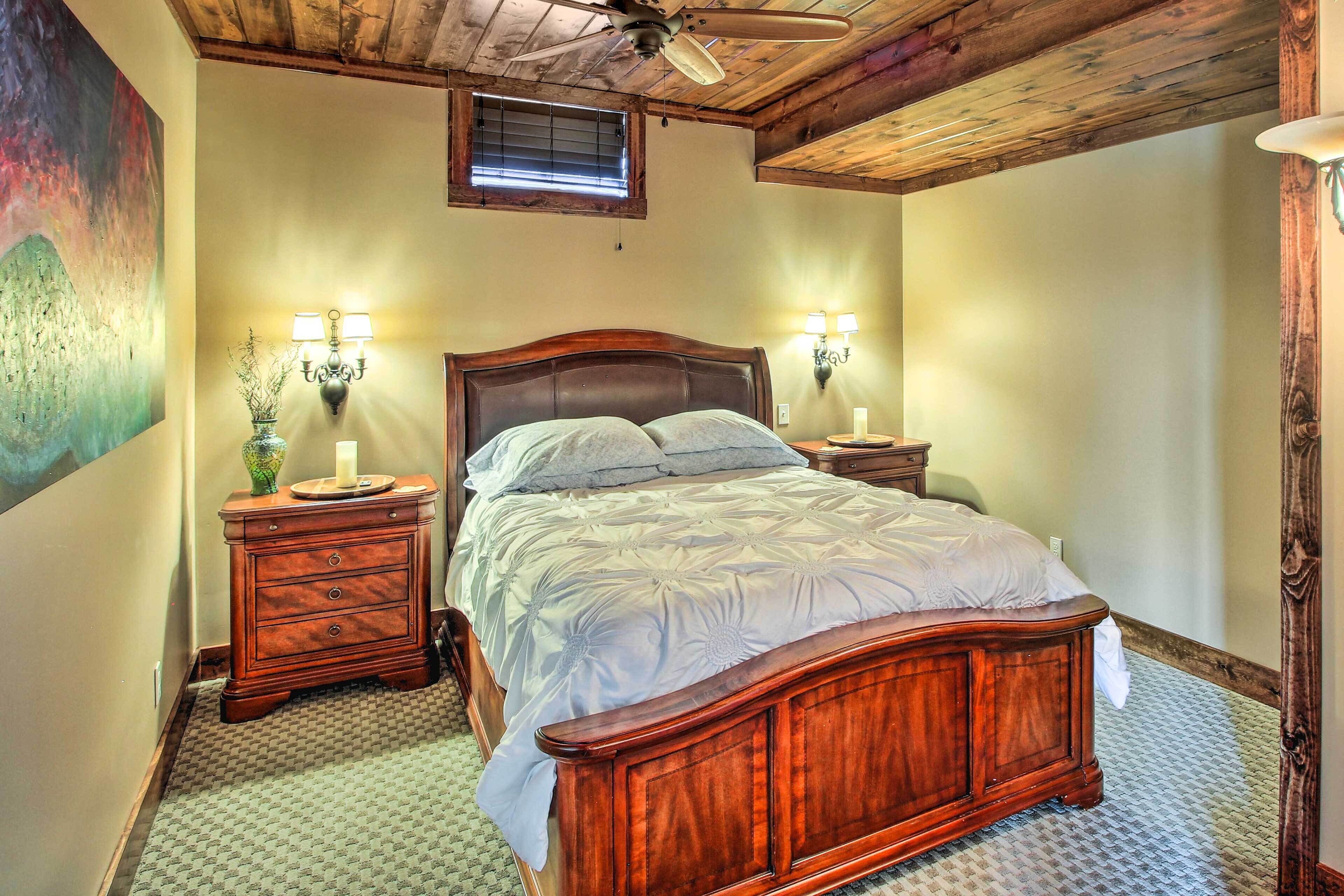 A bedroom with a wooden bed, two bedside tables with lamps, a ceiling fan, and a window with blinds.