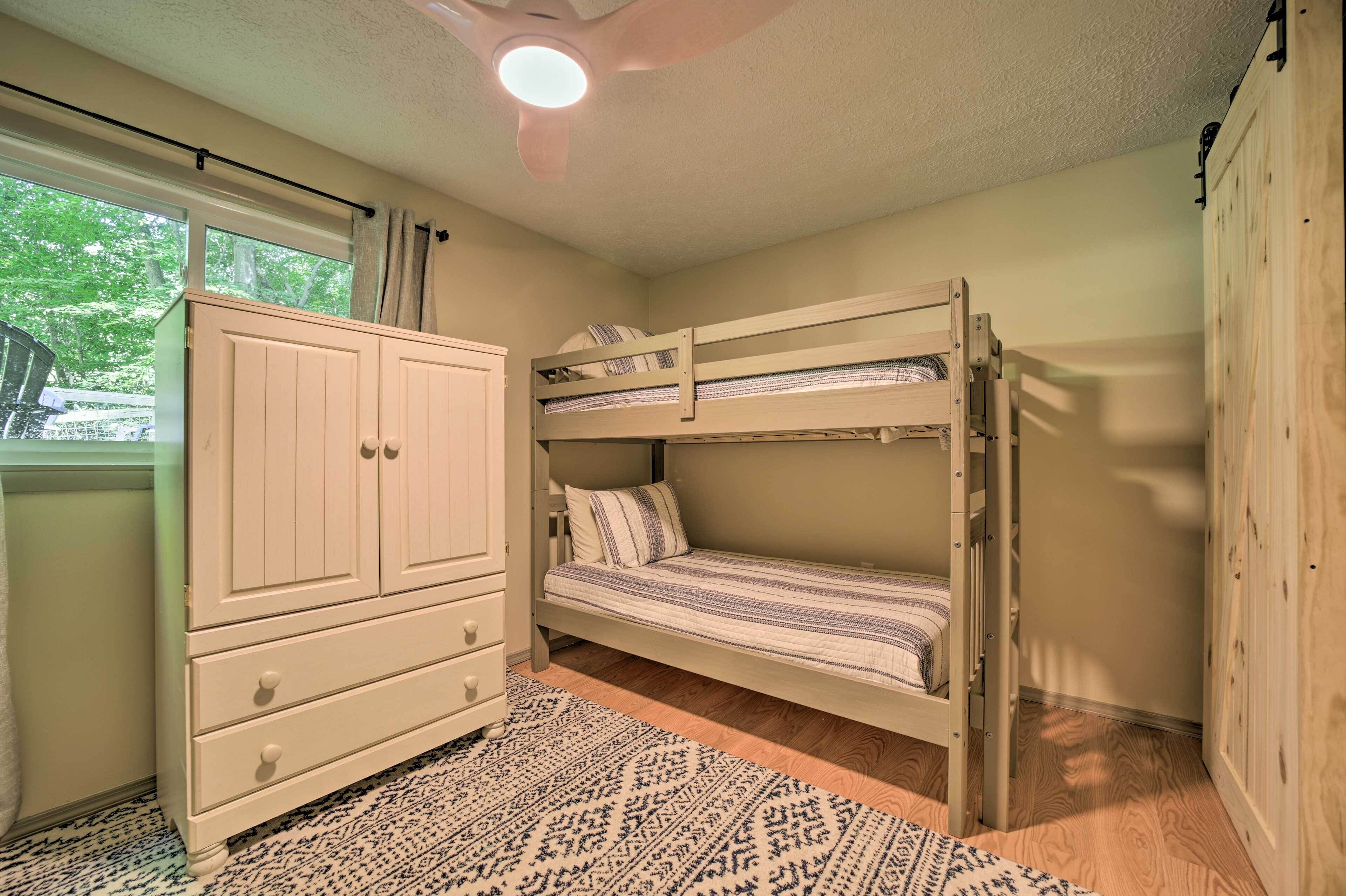 A bedroom with a bunk bed, a wardrobe, and a window with curtains.