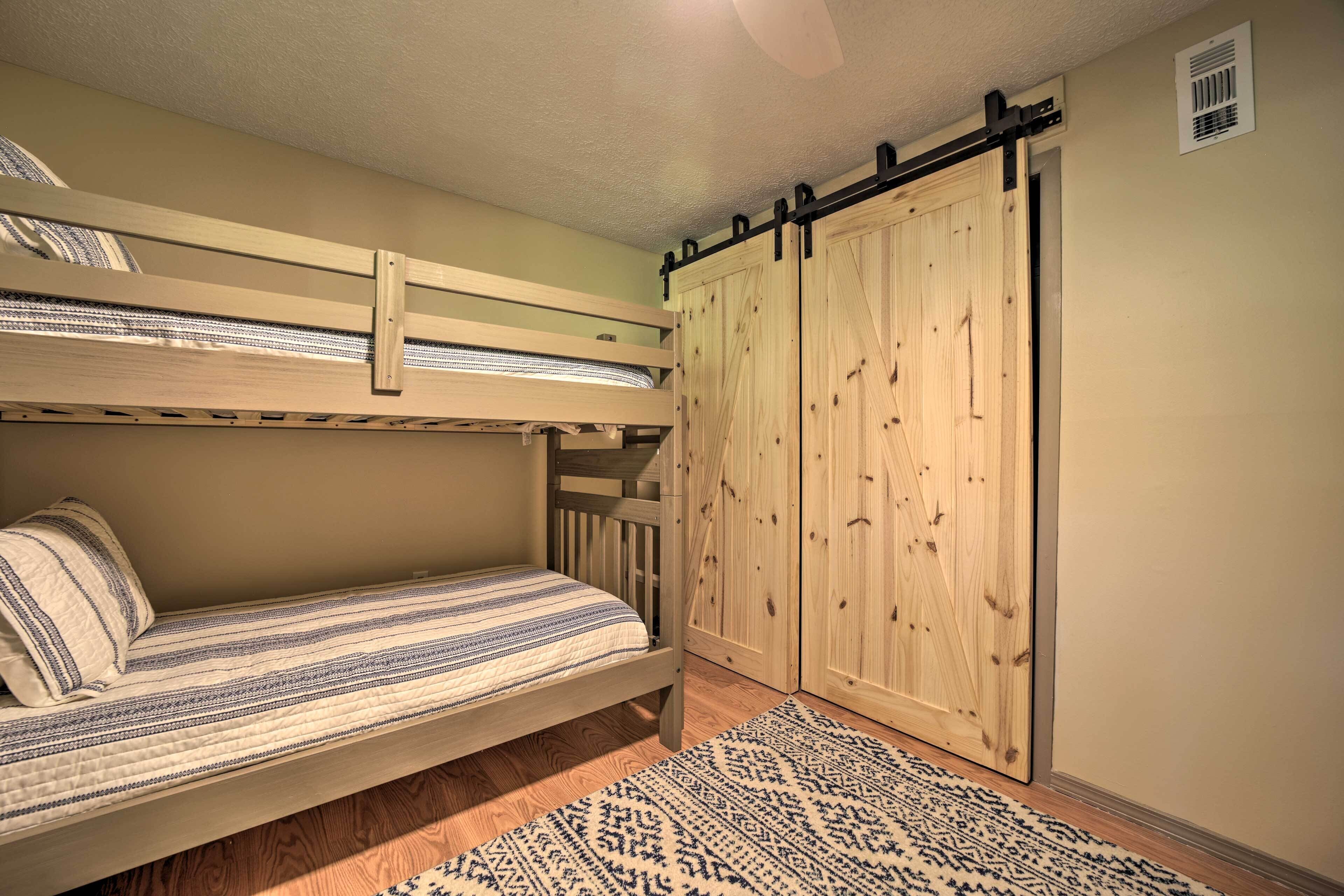 Een stapelbed met een bedspreide met patroon, een houten garderobe met schuifdeur, en een tapijt met patroon op de vloer.