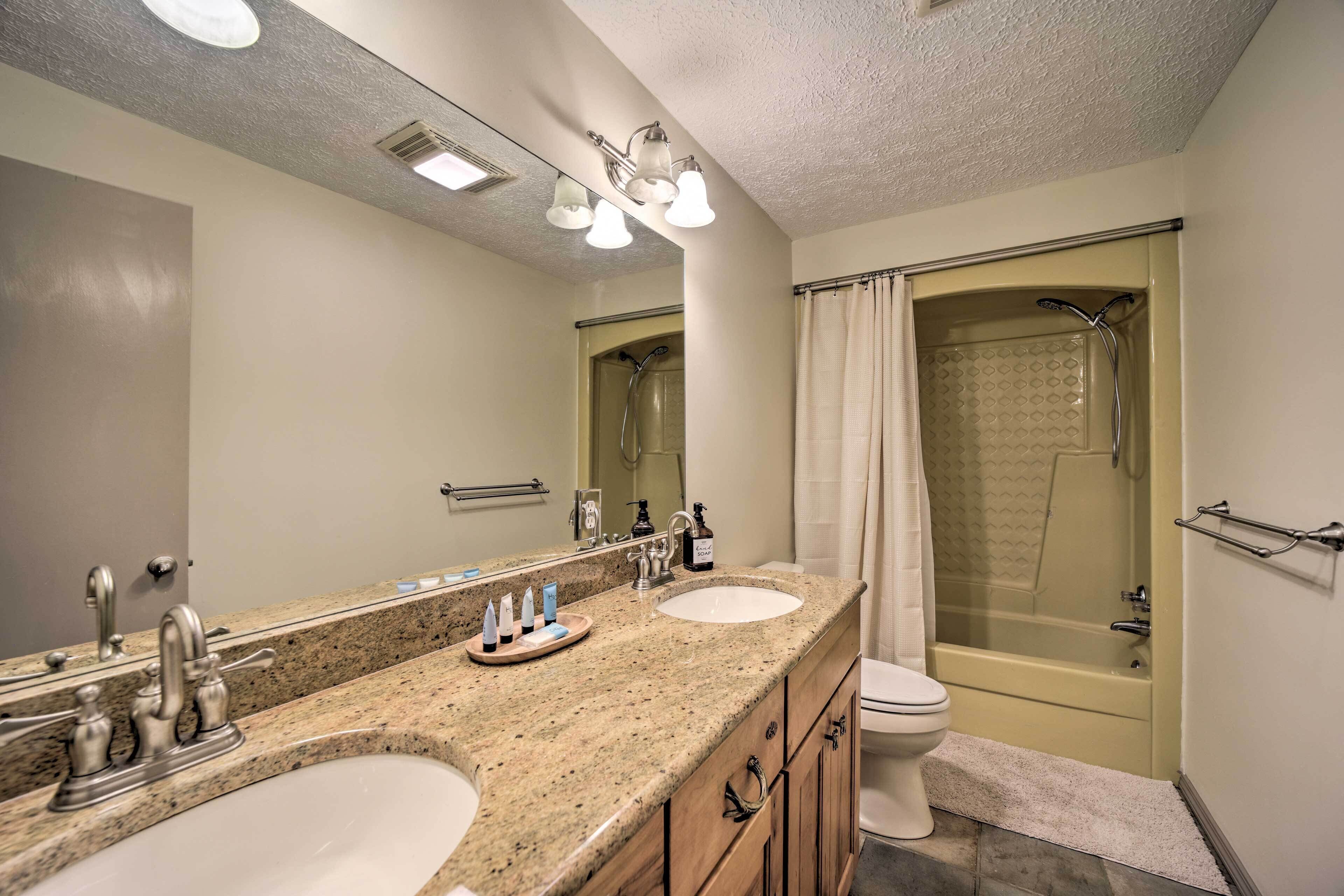 A bathroom with two sinks, a toilet, a shower, and a large mirror.