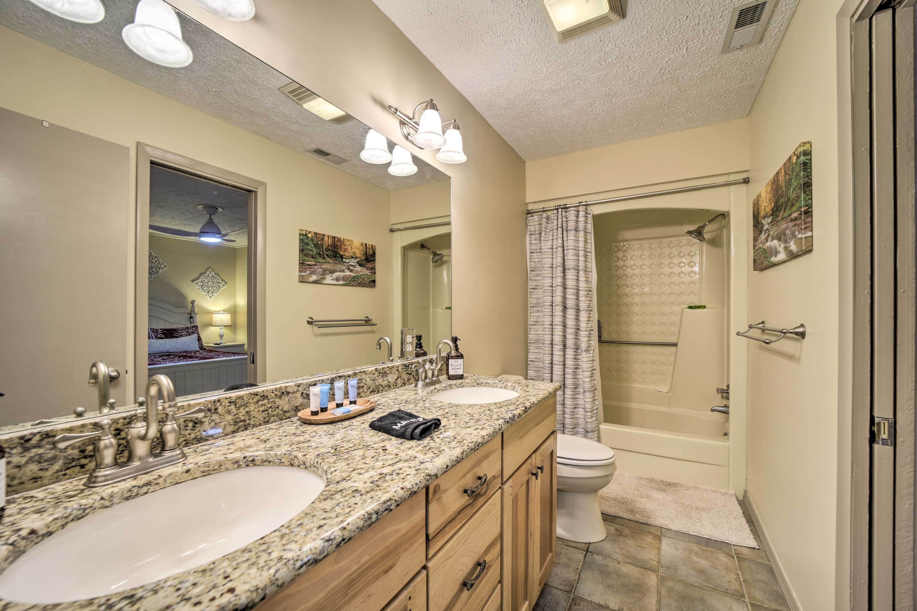 A bathroom with two sinks, a shower, and a toilet.