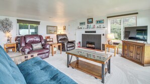 Una sala de estar con chimenea, sillones de cuero, un sofá y una televisión.
