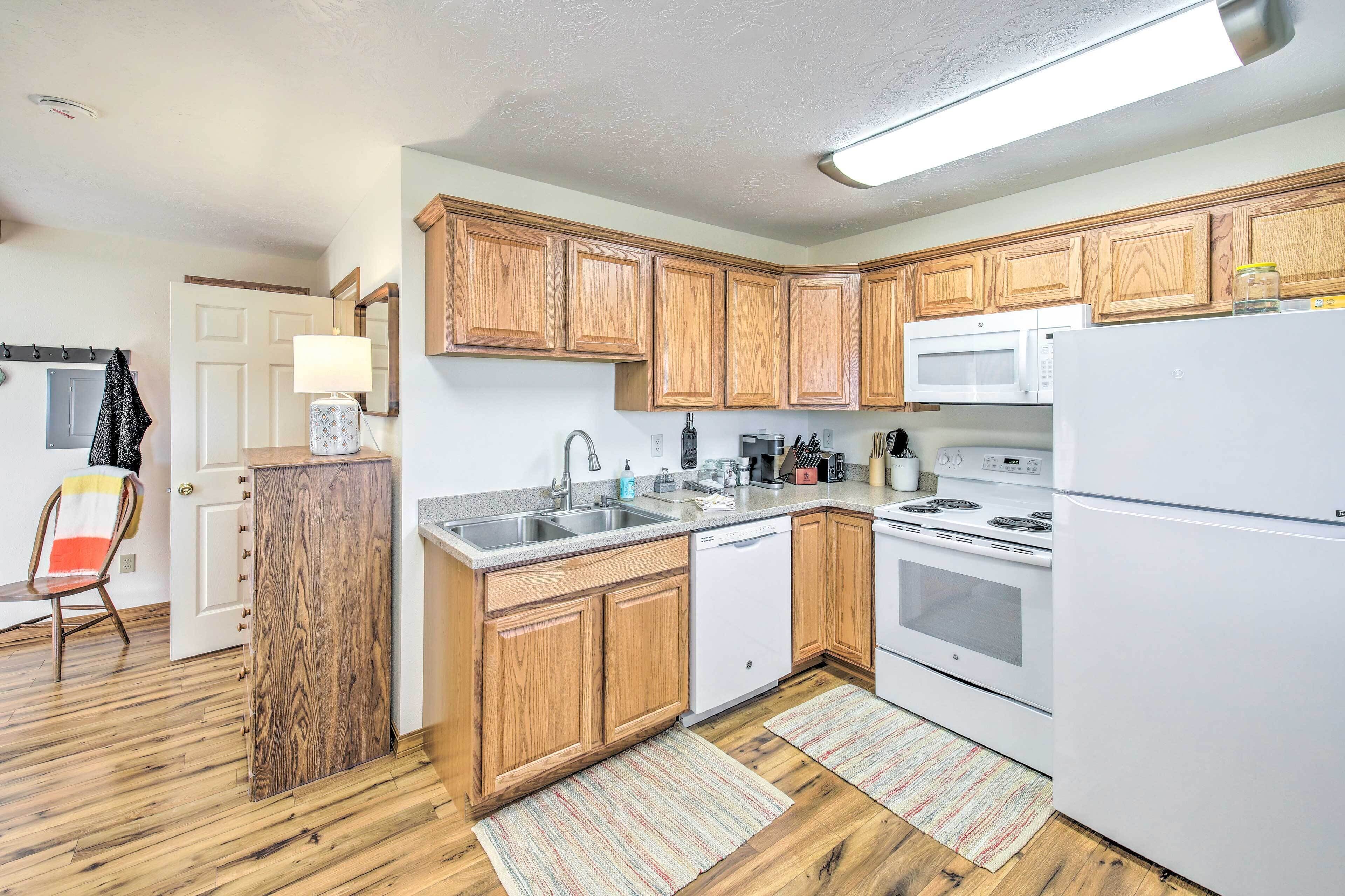 A compact kitchen with wooden cabinets, a microwave, a dishwasher, and a refrigerator.