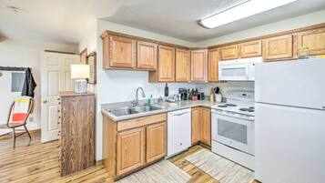 A compact kitchen with wooden cabinets, a microwave, a dishwasher, and a refrigerator.