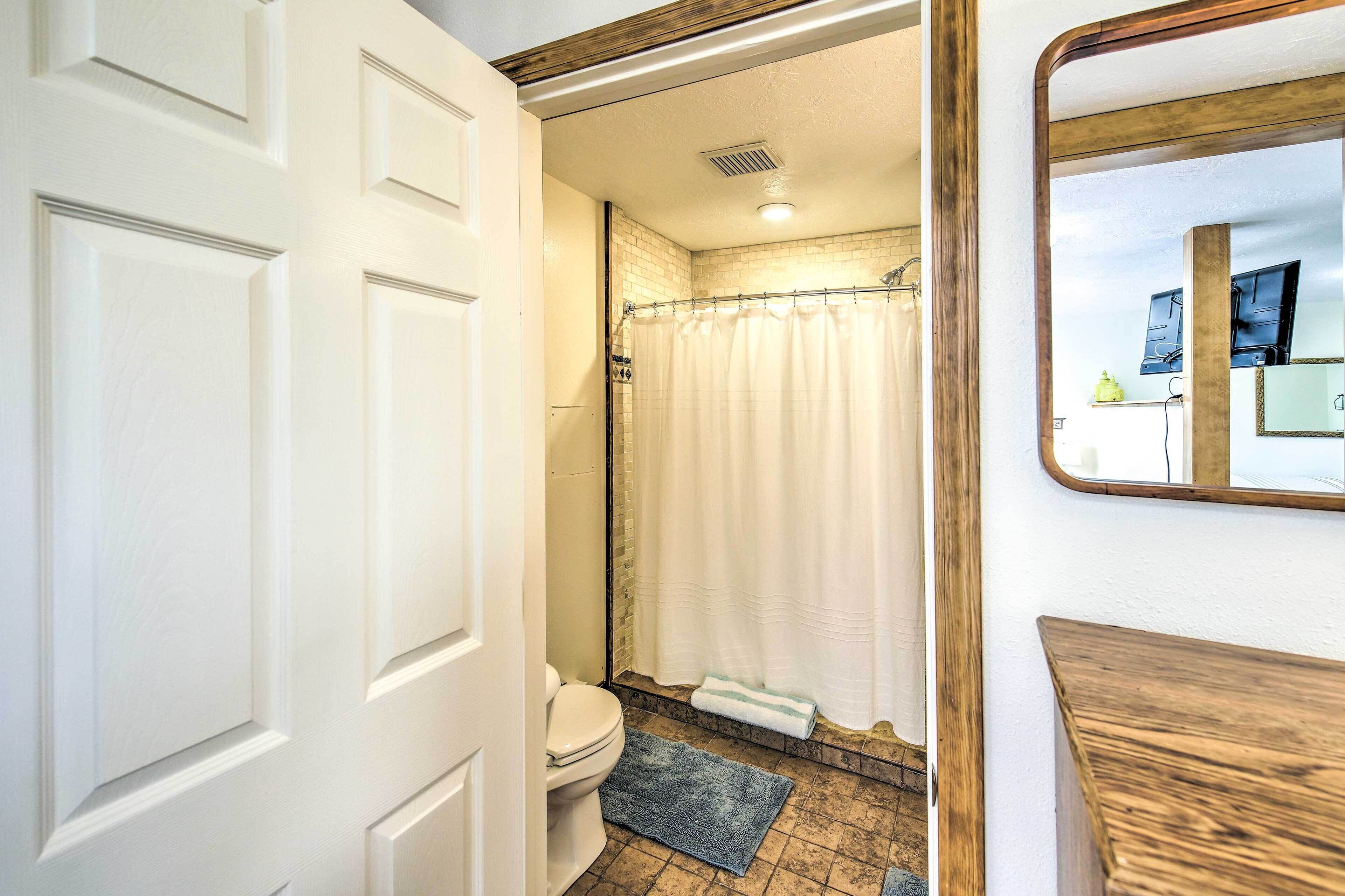 A bathroom with a toilet, shower curtain, and a wooden-framed mirror.
