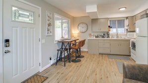 A compact kitchen with a dining area, a clock on the wall, and a refrigerator. - Cozy Roseburg Home w/ Deck + Gas Grill! (Roseburg)