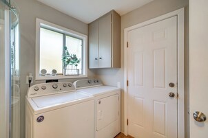 Un lavadero con dos lavadoras Whirlpool, una ventana con una planta y una puerta blanca.