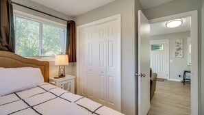 A bedroom with a bed, nightstand, lamp, and a door leading to a hallway. - Cozy Roseburg Home w/ Deck + Gas Grill! (Roseburg)