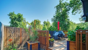A wooden deck with outdoor furniture, surrounded by a wooden fence and various plants. - Cozy Roseburg Home w/ Deck + Gas Grill! (Roseburg)