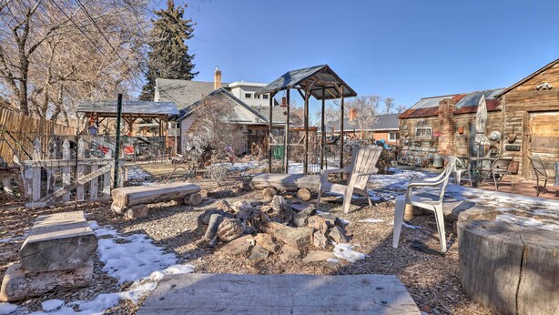 A rustic outdoor area with wooden benches, a covered seating area, and a stone fire pit. - Cozy & Vintage Cedar City Apartment w/ Fire Pit! (Cedar City)