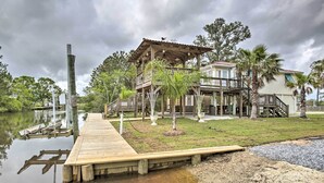 A waterfront property with a wooden dock, a covered outdoor area, and a house with a balcony. - Bay St. Louis House w/ Boat Dock & Launch! (Bay St Louis)