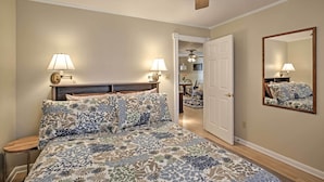 A bedroom with a bed, two bedside lamps, a ceiling fan, a door, and a mirror on the wall. - Bay St. Louis House w/ Boat Dock & Launch! (Bay St Louis)