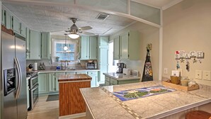 A kitchen with light green cabinets, a wooden island, a ceiling fan, and a backsplash with a tile design. - Bay St. Louis House w/ Boat Dock & Launch! (Bay St Louis)