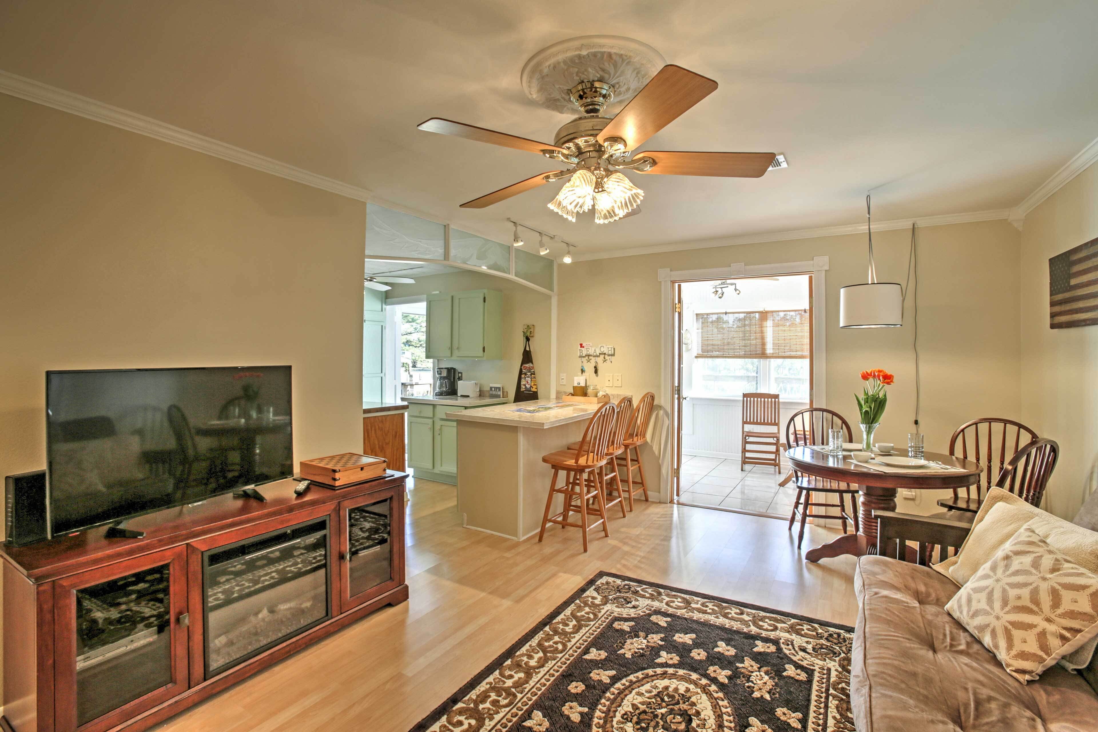 A spacious living room with a television, wooden entertainment unit, and a ceiling fan.