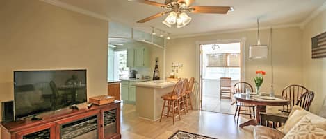 A spacious living room with a television, wooden entertainment unit, and a ceiling fan.