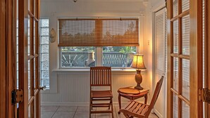 A room with a ceiling fan, large windows with blinds, a chair, a table with a lamp, and wooden doors. - Bay St. Louis House w/ Boat Dock & Launch! (Bay St Louis)