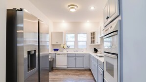 Une cuisine moderne dotée d’appareils électroménagers en acier inoxydable, de meubles blancs et d’un plancher en bois.