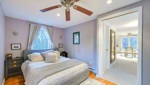 Ein Schlafzimmer mit Bett, Nachttischen, Deckenventilator und Blick in einen anderen Raum.