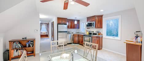 A spacious kitchen with wooden cabinets, a refrigerator, microwave, and a dining area with a glass table and chairs.