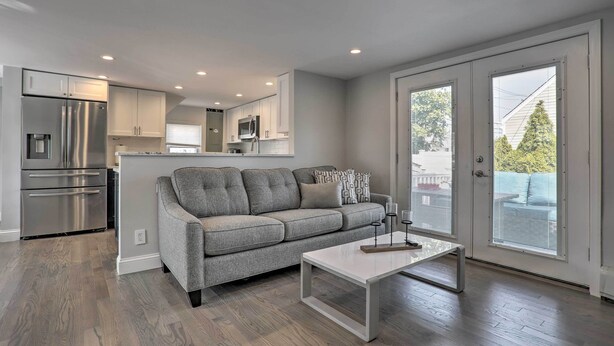 A modern kitchen with stainless steel appliances, a grey sofa, and a white coffee table. - Long Island Home Near Beaches & Golf (Bellmore)
