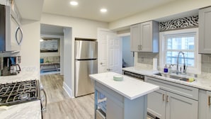 A modern kitchen with a stainless steel refrigerator, a dishwasher, and a marble countertop. - Coastal Comfort & Golfers' Paradise in Sheboygan! (Sheboygan)