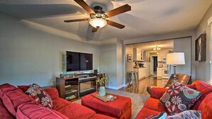 A living room with a red sofa set, a ceiling fan, and a flat-screen TV.