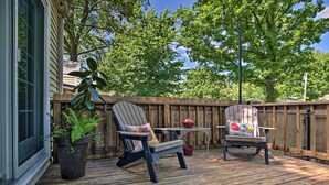 An outdoor deck with two Adirondack chairs, a small table, and a potted plant.