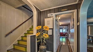 A staircase with green and yellow steps, a vase with sunflowers, and a hallway leading to a living room.