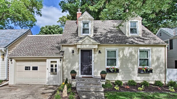A two-story house with a garage, a front porch, and a small garden area.