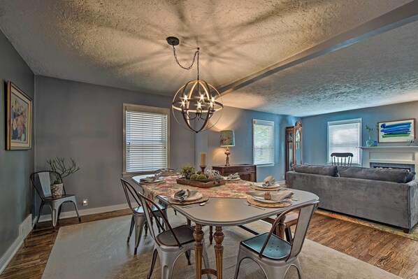 A dining area with a chandelier, a table set for four, and a gray sofa in the background.