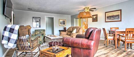 A living room with a rocking chair, a red leather sofa, a wooden coffee table, and a dining area with a table and chairs.