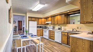 Una cucina compatta con mobili in legno, un frigorifero bianco, un forno a microonde, un forno e un lavello.