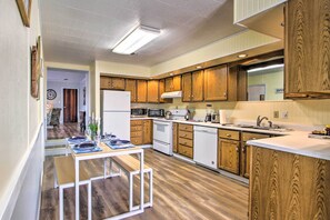 Een kleine keuken met houten kastjes, een witte koelkast, een magnetron, een oven en een spoelbak.