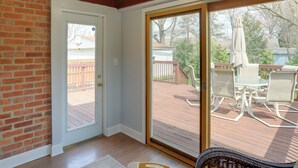 Ein Zimmer mit Holzboden, einer Schiebetür und einer Terrasse mit Gartenmöbeln.
