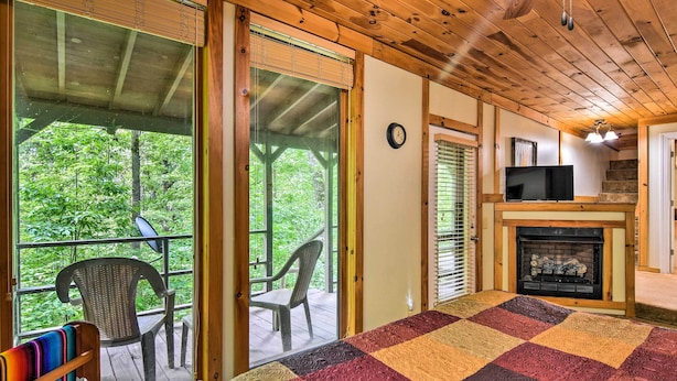 A cozy room with a large bed, a fireplace, and a view of the outdoors. - Robbinsville Cabin w/ Deck: 3 Mi to Fontana Lake! (Robbinsville)